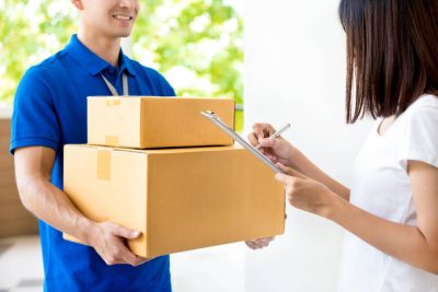stock-photo-woman-signing-document-receiving-parcel-box-from-delivery-man
